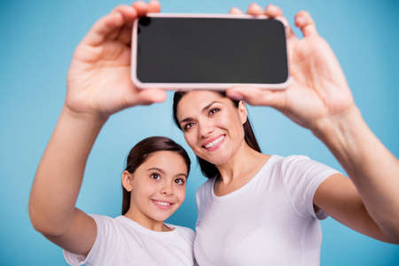 Close-up portrait of two nice cute winsome cheerful cheery people wearing white t-shirt holding in...