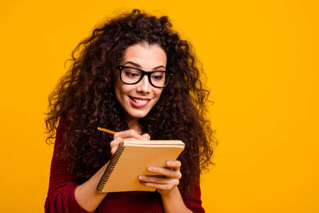 Close-up portrait of her she nice cute attractive clever smart pretty cheerful funny wavy-haired lady writing idea article news academic task isolated over bright vivid shine orange backgroundの写真素材