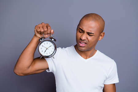 Close up photo sick unhealthy masculine dark skin he him his macho bald head puzzled hold steel clock hate going work early disgusted wearing white t-shirt outfit clothes isolated grey backgroundの写真素材