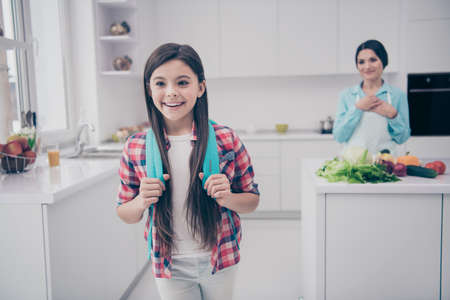 Portrait of two nice-looking lovable adorable lovely sweet attractive cheerful positive people mature kind careful mum see off pre-teen girl in light white kitchen interior indoorsの写真素材
