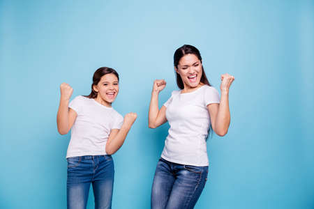 Close up photo cheer pretty two people brown haired mum small little daughter  arms up in air gladly yelling got free sale discount shopping wear white t-shirts isolated bright blue backgroundの写真素材