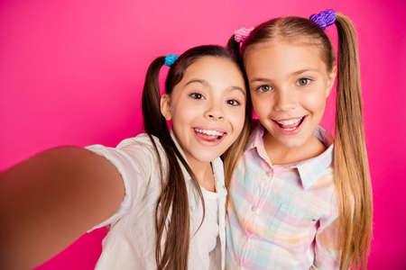 Close up photo two small little age she her girls make take summer camp selfies for relatives bonding glad wearing casual jeans denim checkered plaid shirts isolated rose vibrant bright backgroundの写真素材