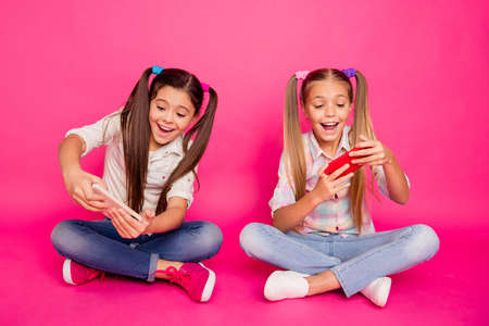 Close up photo two people little age she her girls hold hands arms telephones sit floor involved...