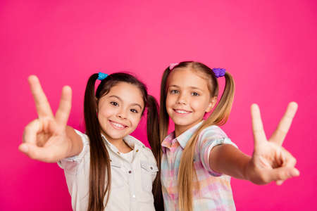 Close up photo two small little age she her girls hands arms palms show v-sign say hi mom dad parents wearing casual jeans denim checkered plaid shirts isolated rose vibrant vivid backgroundの写真素材