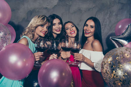 Portrait of nice lovely adorable fascinating chic attractive glamorous shine gorgeous cheerful cheery ladies many different baloons clinking red wine over gray concrete wallの写真素材