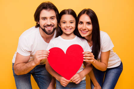 Portrait of nice cute sweet lovely attractive cheerful people holding in hands big large red paper card isolated over shine vivid pastel yellow backgroundの写真素材