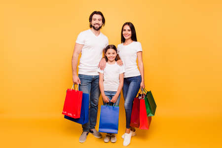 Full length body size view portrait of nice attractive adorable trendy cheerful people holding in hands bags with new clothes isolated over shine vivid pastel yellow backgroundの写真素材
