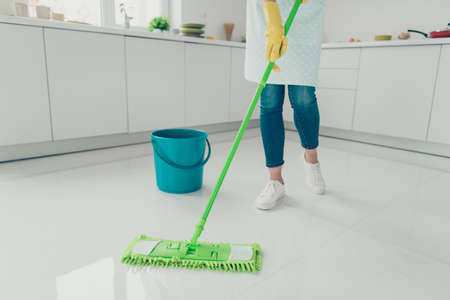 Cropped view of her she house-wife cleansing polishing shine floor parquet tile in modern light white interior indoorsの写真素材