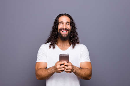 Portrait of nice groomed attractive cheerful cheery positive optimistic wavy-haired guy using new...