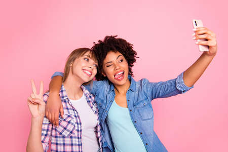 Portrait of her she two person nice attractive charming cheerful cheery girls wearing casual checkered shirt making selfie showing v-sign isolated over pink pastel backgroundの写真素材