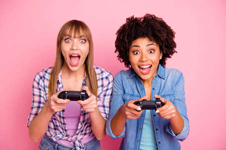 Close-up portrait of two person nice crazy fascinating lovely attractive charming cheerful excited girls in casual checkered shirt playing online having fun isolated over pink pastel backgroundの写真素材