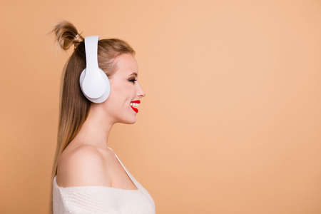 Profile side view portrait of her she nice-looking fascinating attractive lovely glamorous cheerful caucasian straight-haired girl listening rock pop jazz funk isolated on beige pastel backgroundの写真素材