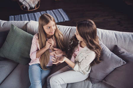 Top above high angle view of two nice sweet lovely attractive cheerful girls discussing news sitting on divan in house indoorsの写真素材