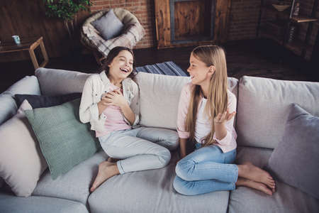 Above high angle view portrait of two nice lovely attractive charming cheerful cheery girls sharing discussing funny dream news memories sitting on divan in house loft industrial interior styleの写真素材
