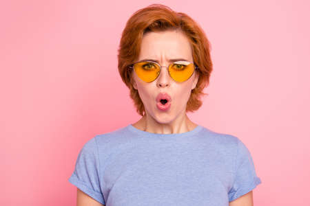 Close-up portrait of her she nice cute charming attractive lovely stunned girl wearing casual blue t-shirt yellow glasses opened mouth pouted lips isolated over pink pastel backgroundの写真素材