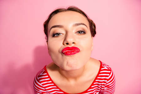 Close-up portrait of her she nice-looking cute attractive glamorous cheerful cheery crazy girl wearing striped t-shirt showing red lips air blow kiss isolated over pink pastel backgroundの写真素材