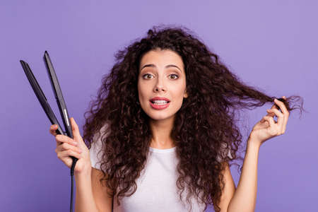 Close-up portrait of nice cute lovely attractive winsome wavy-haired lady holding in hand new electric product hot temperature care device isolated on bright vivid shine violet pastel backgroundの写真素材