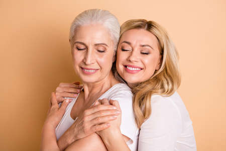 Close-up portrait of nice attractive charming sweet tender lovely cheerful cheery ladies supporting granny mom mommy mum cheering up isolated over beige pastel backgroundの写真素材