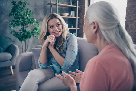 Close up photo two beautiful she her ladies mom granddaughter child granny tell speak say share secrets best buddies funny life story sit comfy cozy couch divan sofa flat house indoorsの写真素材
