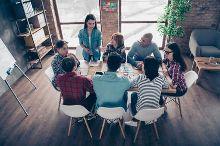 Interested pensive partners guys partnership listening to millennial lady coworker presenting explaining successful project analyzing communicating wearing casual shirts in modern officeの写真素材