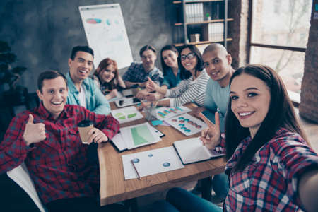 Professional managers girls guys coworking partners partnership make photos show gestures v-signs peace thumb-up like fine  advertising recommending give feedback in casual shirts in officeの写真素材