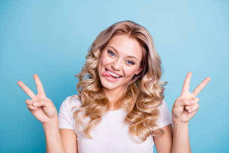 Close up photo amazing beautiful her she lady laugh tongue out mouth hands arms fingers show v-sign say hi playing wear casual white t-shirt jeans denim clothes outfit isolated blue backgroundの写真素材