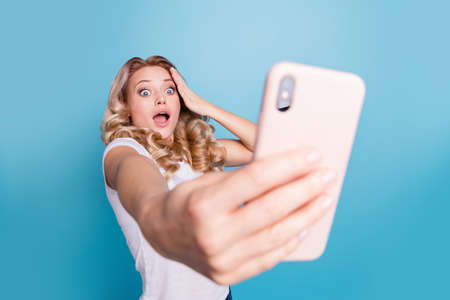 Portrait of her she nice-looking lovely feminine fascinating attractive cheerful funny funky wavy-haired lady holding in hands cell smm blog post isolated over blue pastel backgroundの写真素材