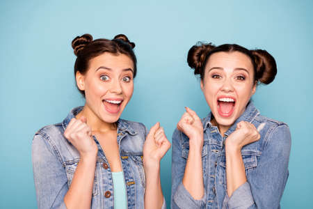 Close up photo of cute funny cheerful isolated teenagers impressed by incredible news events raising fists hands yelling loudly opening mouth wearing modern denim clothing on blue backgroundの写真素材