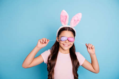 Closeup photo portrait of lovely pretty careless cute nice glad charming optimistic enjoying free time girl holding painted colored dotted eggs on sticks in hands isolated pastel backgroundの写真素材