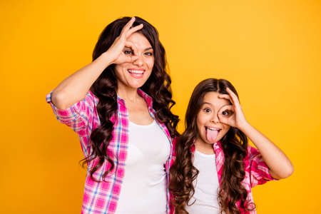 Portrait of nice attractive cheerful positive crazy foolish wavy-haired girls wearing checked shirt showing ok-sign like glasses isolated over bright vivid shine yellow backgroundの写真素材