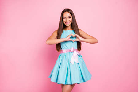 Portrait of lovely model cute teenager teen showing affection attracting boys males men making heart with fingers isolated dressed in bright clothing on rose-colored backgroundの写真素材