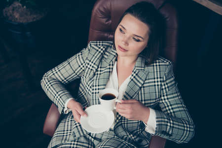 Close up top above high angle photo amazing beautiful she her business lady hold arms hands white glass hot coffee look side sit big large office cozy chair wear formal-wear checkered plaid suitの写真素材