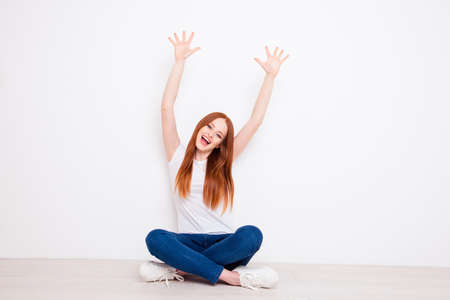 Full length body size photo beautiful she her lady sit floor legs crossed hands arms palms raised up excitement yelling delight wear casual t-shirt jeans denim outfit clothes isolated white backgroundの写真素材