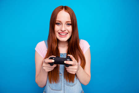 Close up photo beautiful amazing she her lady funny hold hands arms video game controller hard match worry team success want win wear casual jeans denim overalls clothes isolated blue backgroundの写真素材