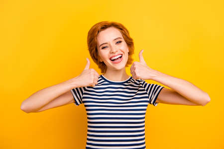 Close up photo beautiful amazing she her lady easy-going thumb up amazed glad advising new product wearing casual striped white blue t-shirt outfit clothes isolated yellow bright vibrant backgroundの写真素材