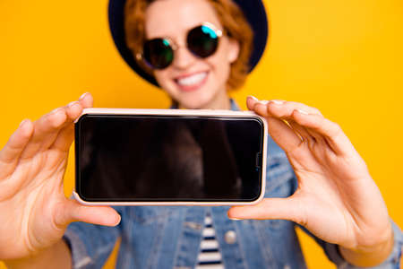 Close up photo foxy she her lady modern look telephone make take selfies speak tell skype wear specs vintage hat casual striped t-shirt jacket jeans denim isolated yellow bright blurred backgroundの写真素材