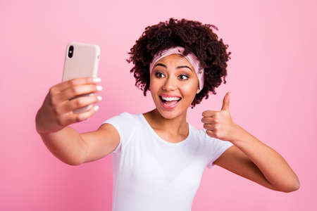 Close-up portrait of nice charming cute attractive lovely winsome cheerful cheery wavy-haired girl taking making selfie showing thumbup isolated over pink pastel backgroundの写真素材