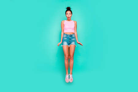 Full length body size photo beautiful she her jump high not believe eyes so big great success trendy stylish hairdo wear casual pink tank-top jeans denim shorts isolated teal turquoise backgroundの写真素材