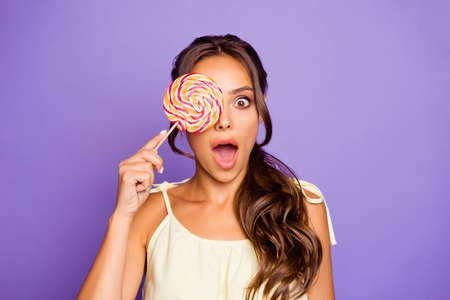 Closeup photo portrait of single charming gorgeous nice glad positive optimistic crazy  lady holding colorful round red and white candy isolated violet background.の写真素材