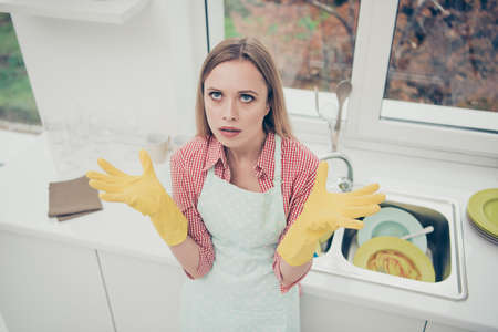 Close up photo beautiful she her lady not fear helpless expression cleaner bright kitchen dirty plates sink cleanup hate dislike house duties bad mood wear casual jeans denim shirt apron flat indoors