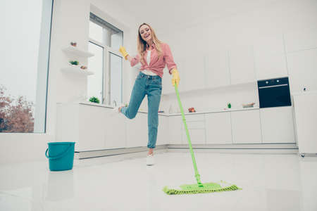 Full length body size photo beautiful domestic duties she her lady rhythms motion wash white shiny floor listen playlist audio sound wear jeans denim casual checkered plaid shirt bright light kitchenの写真素材