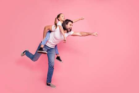 Full length side profile body size photo she her little lady he him his daddy dad hold little princess piggyback hands arms ready fly wear casual white t-shirts denim jeans isolated pink background