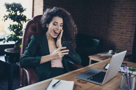 Portrait of cute lovely ceo have break relax rest sit chair look news feed impressed incredible information scream shout use gadget modern technology table stylish black blazer in interiorの写真素材