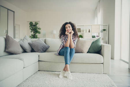 Portrait of pretty lovely friendly youth student have holidays vacation feel content rejoice touch hand chin wear checked denim outfit white sneakers in big apartmentの写真素材