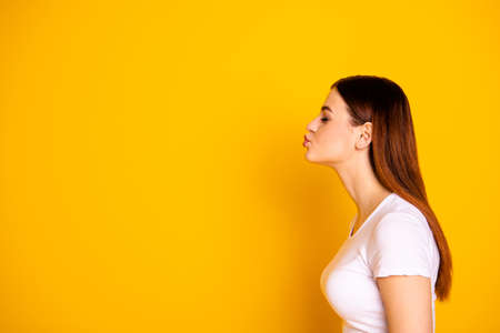 Close up side profile photo beautiful  lady wait send air kisses empty space long straight perfect hair eyes closed attractive appearance wear casual white t-shirt isolated yellow background.の写真素材