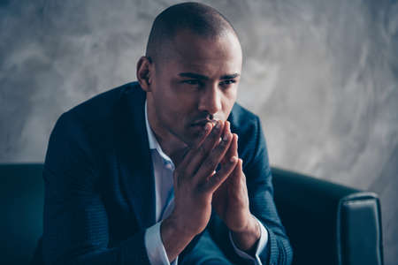 Close-up portrait of his he nice stylish classy guy wearing jacket executive director top manager ceo boss chief sitting on couch thinking praying at workplace workstation concrete wall.の写真素材