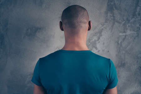 Rear back behind view portrait of his he nice strong guy wearing trendy blue t-shirt modern look isolated over gray industrial concrete wall.の写真素材
