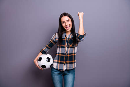 Close up photo amazing beautiful she her lady hold hand arm raised air leather football soccer ball yelling triumphing crazy wear casual jeans denim checkered plaid shirt isolated grey backgroundの写真素材