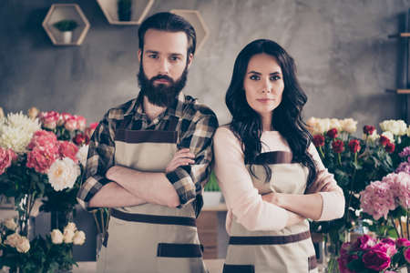 Close up photo beautiful she her wife lady him his he husband macho guy stand back near compositions bunches fresh flowers ready start earn money strict faces owners small flower shop room indoorsの写真素材