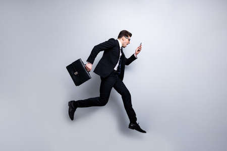 Full length body size profile side view portrait of his he nice classy attractive nervous worried guy carrying in hands diplomat cell white collar rush hour career growth isolated on light gray backgroundの写真素材